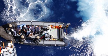 Rescued migrants sit in a German Navy boat besides Finnish Special Forces prior to board the German combat supply ship &quot;Frankfurt am Main&quot; in the Mediterranean Sea off the coast of Libya, March 29, 2016. (AP Photo)