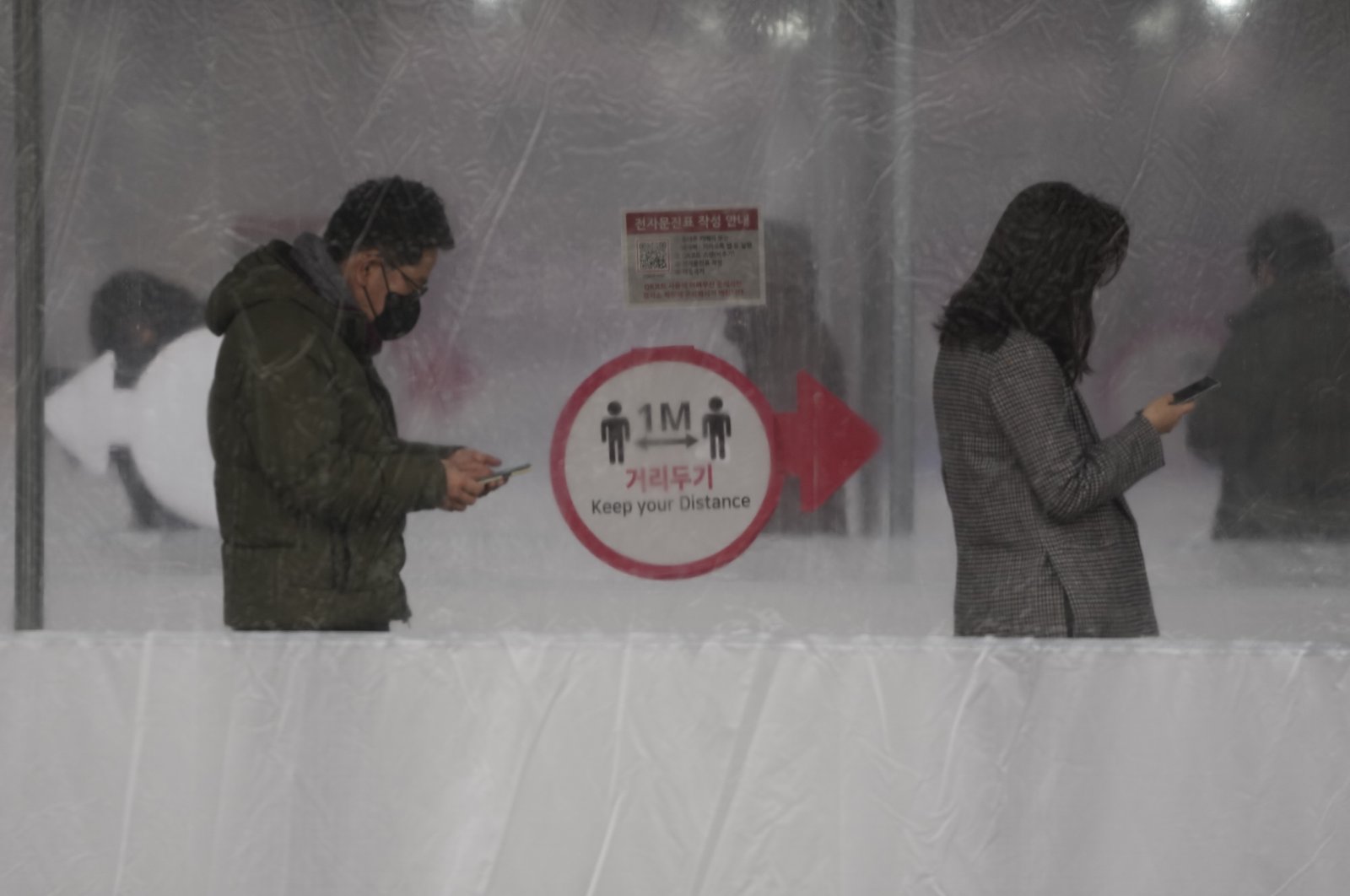 People queue in line for a COVID-19 test while maintaining social distancing at a temporary screening clinic for the coronavirus in Seoul, South Korea, Jan. 25, 2022. (AP Photo)