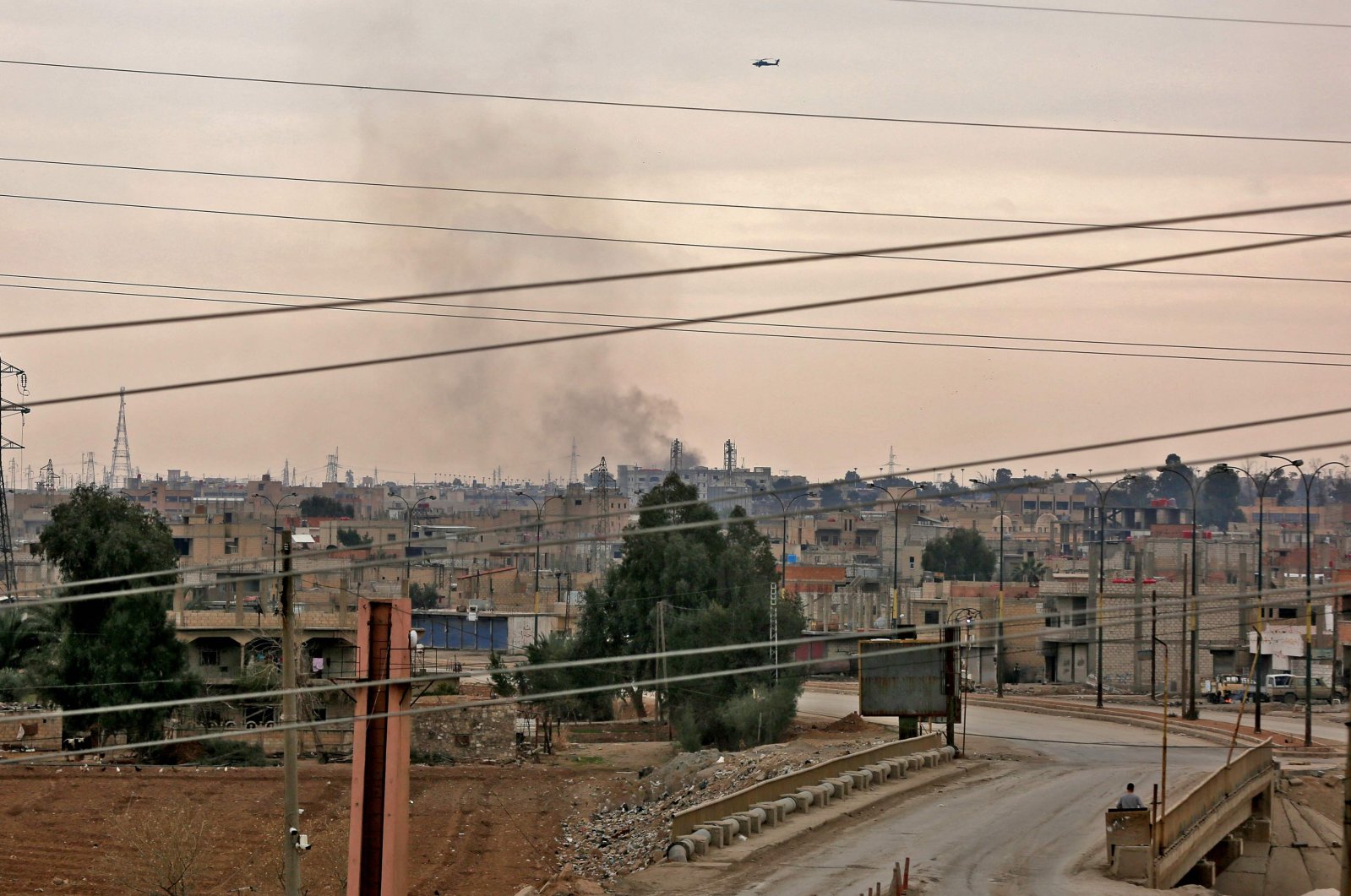 A helicopter flies over the city as smoke billows in the northern Syrian city of Hassakeh, Jan. 24, 2022. (AFP Photo)