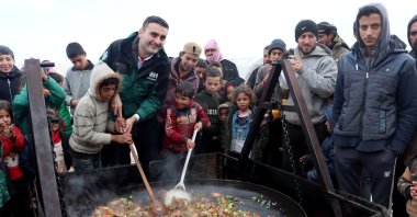 Celebrity chef Burak Özdemir, popularly known as CZN Burak, cooks with children at a refugee camp in Idlib, northwestern Syria, Jan. 26, 2022. (AA Photo)