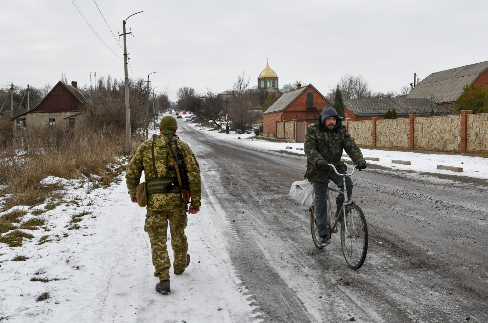 A Ukrainian service officer patrols a street near the front line with Russia-backed separatists in the village of Verkhnotoretske in the Yasynuvata district, Donetsk region, eastern Ukraine, Jan. 22, 2022. (AP Photo)