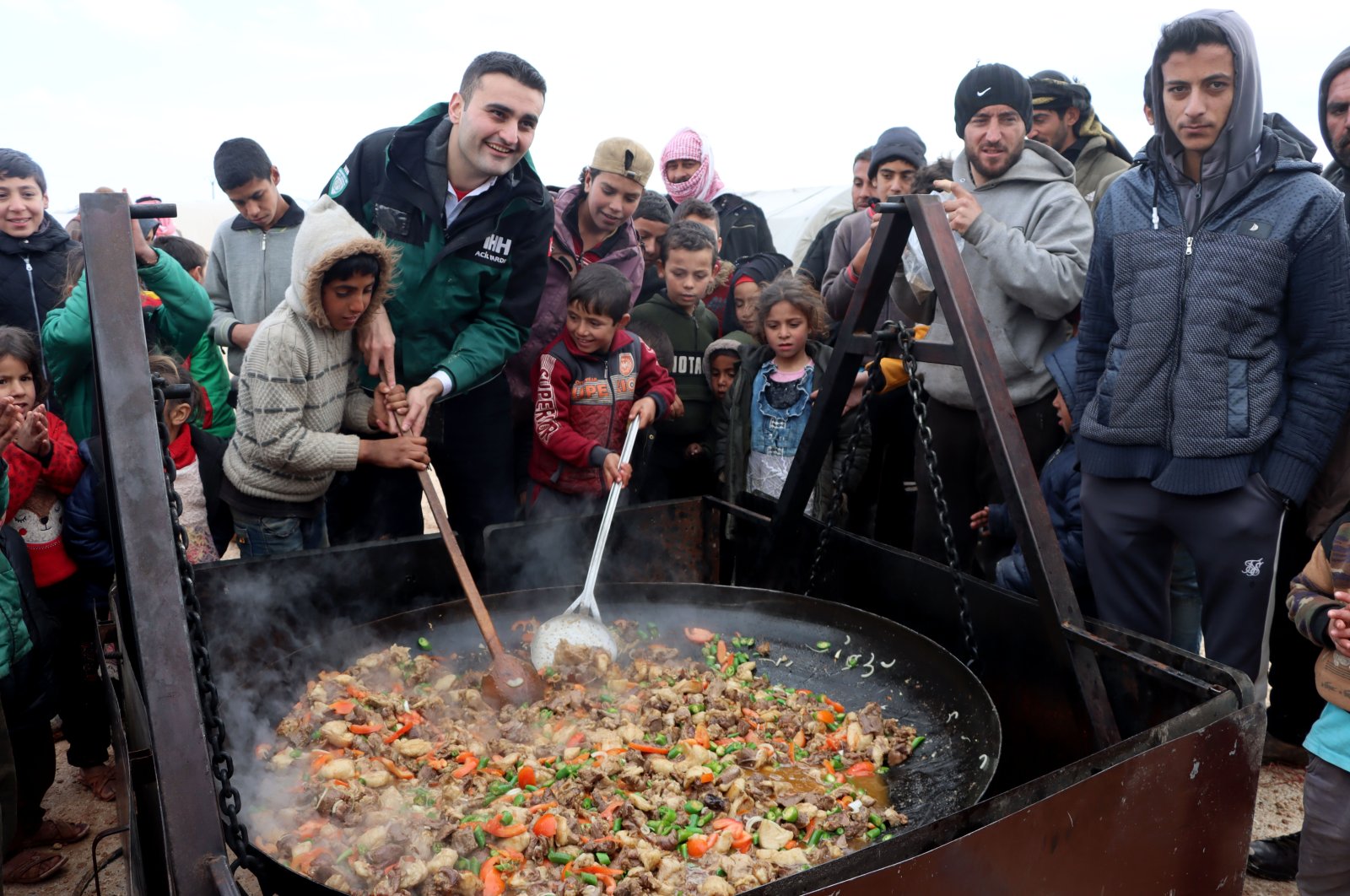 Celebrity chef Burak Özdemir, popularly known as CZN Burak, cooks with children at a refugee camp in Idlib, northwestern Syria, Jan. 26, 2022. (AA Photo)