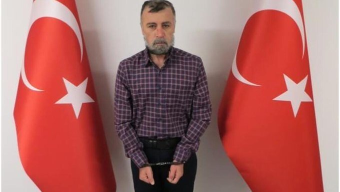 Nuri Gökhan Bozkır poses in front of Turkish flags after being detained in an operation by MIT, in this photo released on Jan. 27, 2022. (MIT handout)