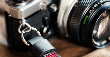 Vintage film camera with leather wrist strap. (Shutterstock Photo) 