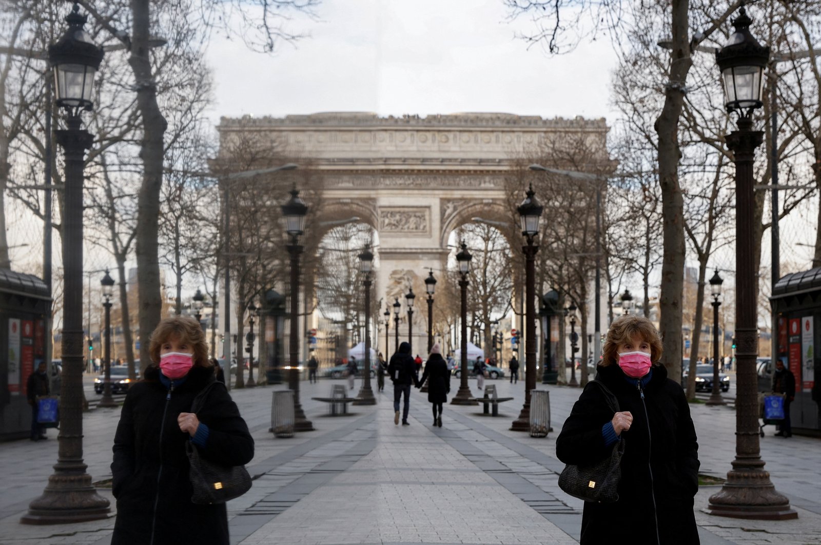 A woman wearing a protective face mask walks near the Arc de Triomphe on the Champs Elysees Avenue in Paris amid the coronavirus outbreak in France, Jan. 21, 2022. (Reuters Photo)