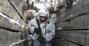 An armed serviceperson walks along a trench on the territory controlled by pro-Russian militants on the frontline with Ukrainian government forces near Spartak village in Yasynuvata district of Donetsk region, eastern Ukraine, Jan. 27, 2022. (AP Photo)