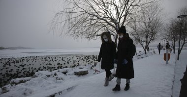 People wearing protective masks against COVID-19 walk past Mogan Lake, in the capital Ankara, Turkey, Jan. 25, 2022. (AP Photo)
