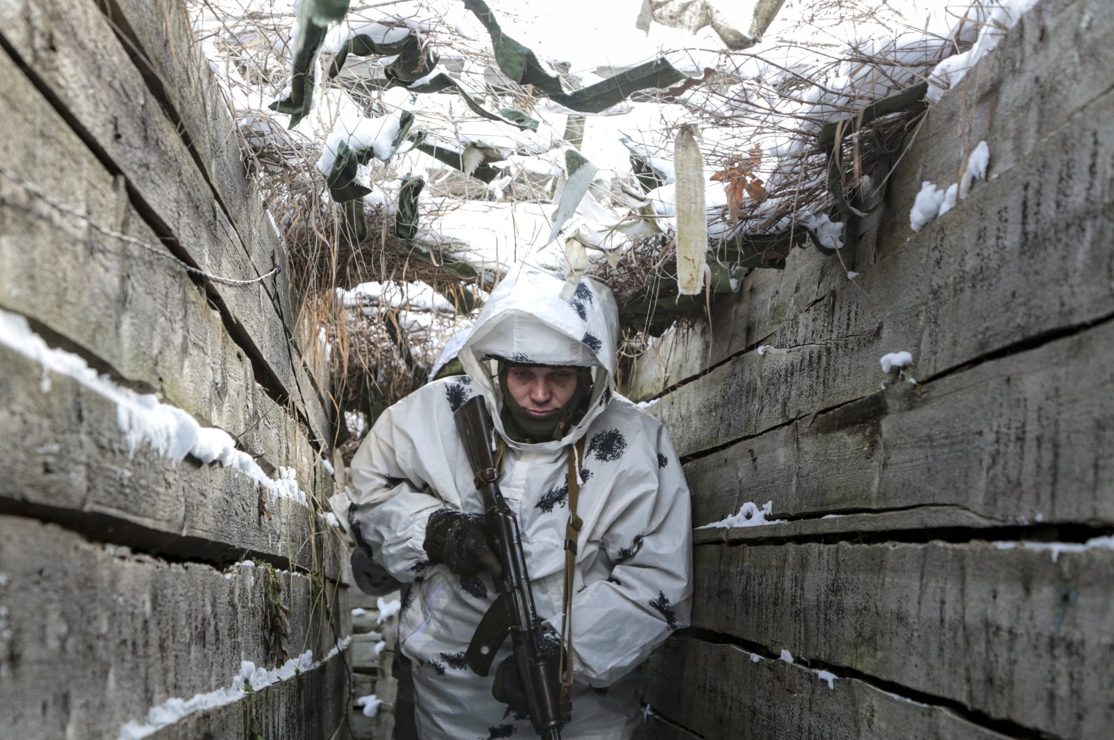 An armed serviceperson walks along a trench on the territory controlled by pro-Russian militants on the frontline with Ukrainian government forces near Spartak village in Yasynuvata district of Donetsk region, eastern Ukraine, Jan. 27, 2022. (AP Photo)