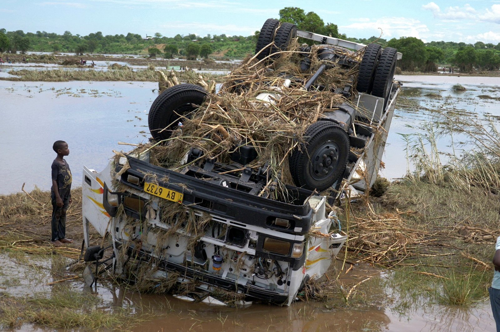 Locals look at a wreck washed away during tropical storm Ana on the flooded Shire river, an outlet of Lake Malawi at Thabwa village, in Chikwawa district, southern Malawi, Jan. 26, 2022. (Reuters Photo)