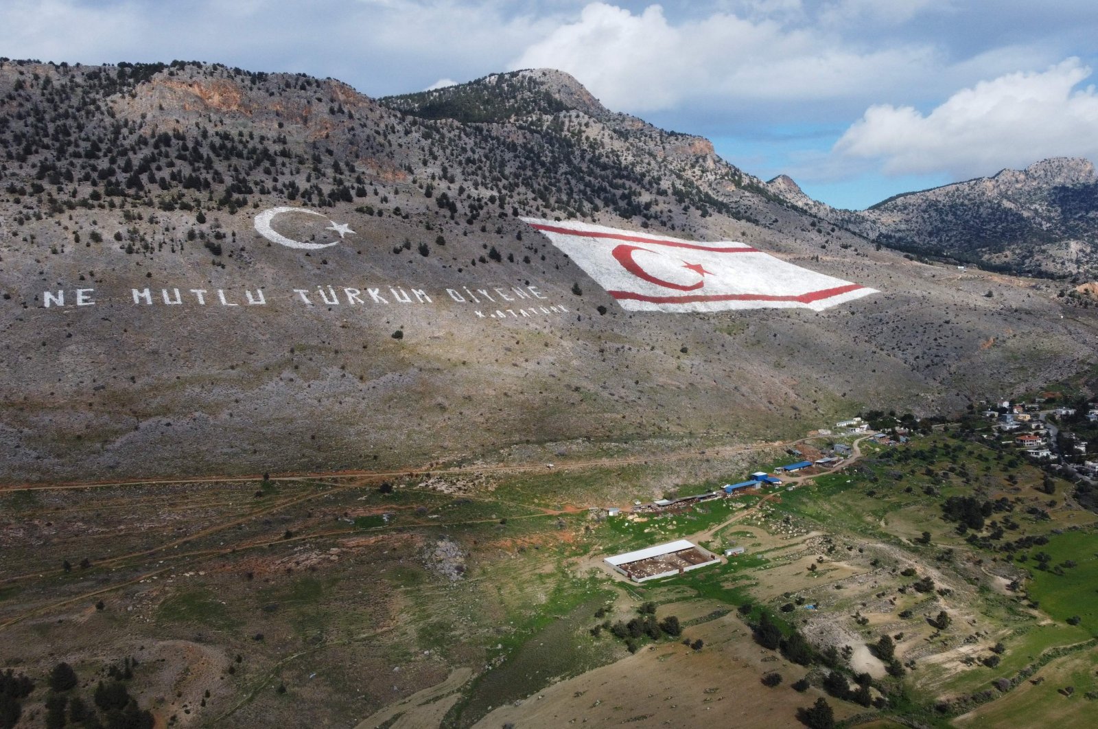 An aerial picture shows the flag of the Turkish Republic of Northern Cyprus (TRNC) next to a quote by the founder of the Turkish republic, Mustafa Kemal Ataturk, reading in Turkish: &quot;Happy are they who call themselves a Turk,&quot; painted on the Kyrenia (Girne) mountain range north of Nicosia (Lefkoşa), TRNC, Jan. 22, 2022. (AFP Photo)