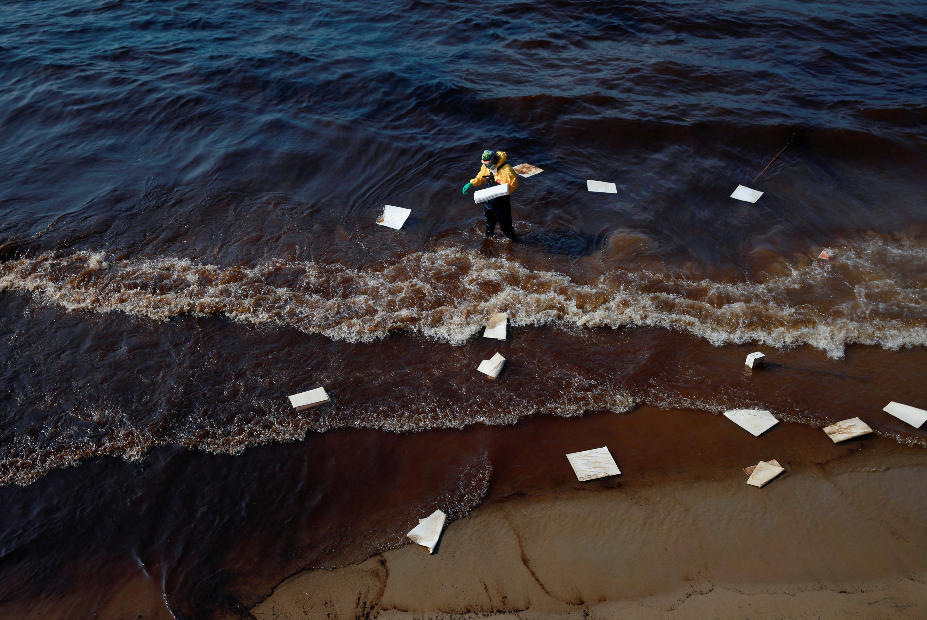 Seorang pekerja membersihkan tumpahan minyak yang disebabkan oleh kebocoran dari pipa bawah laut 20 km (12,4 mil) di lepas pantai timur Thailand di pantai Mae Ramphueng di provinsi Rayong, Thailand, 29 Januari 2022. (Foto Reuters)