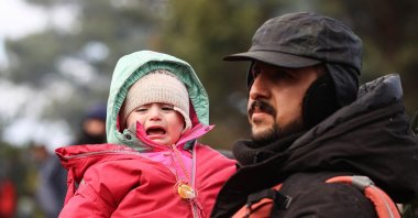 A man holds a child on the Belarusian-Polish border on Nov. 8, 2021. (TASS via Getty Images)