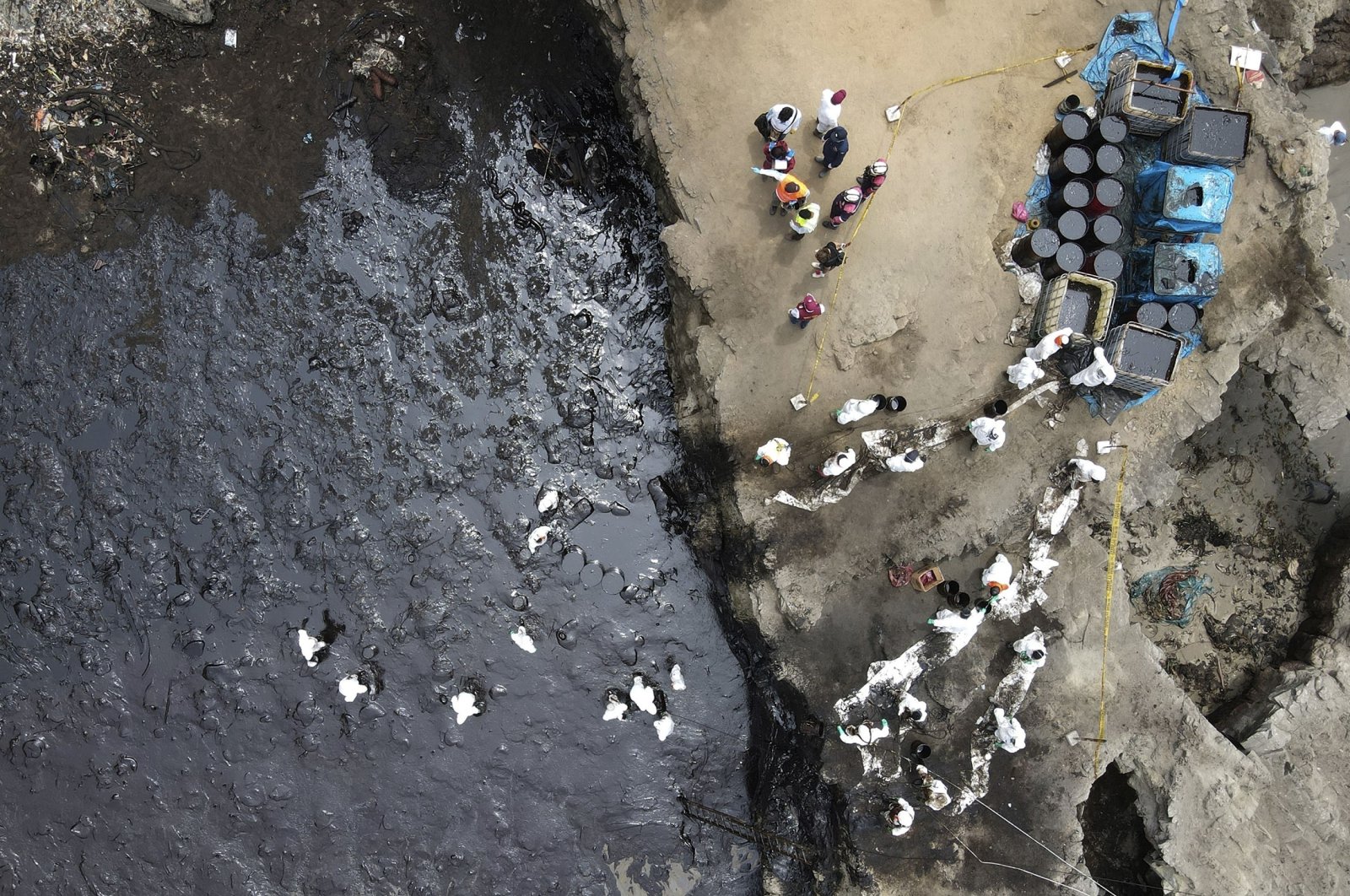 Workers continue in a clean-up campaign after an oil spill, on Cavero Beach in the Ventanilla district of Callao, Peru, Jan. 22, 2022. (AP Photo)