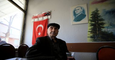 Ali Özgüler sits in a coffeehouse in front of a portrait of Atatürk, who is credited with the population exchange, in Kırklareli, northwestern Turkey, Jan. 29, 2022. (AA Photo)