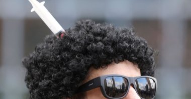 A man wearing a wig with a syringe in it takes part in a demonstration asking for the impeachment of Belgium's government after restrictions imposed to contain the spread of COVID-19, Brussels, Belgium, Jan. 30, 2022. (Reuters Photo)
