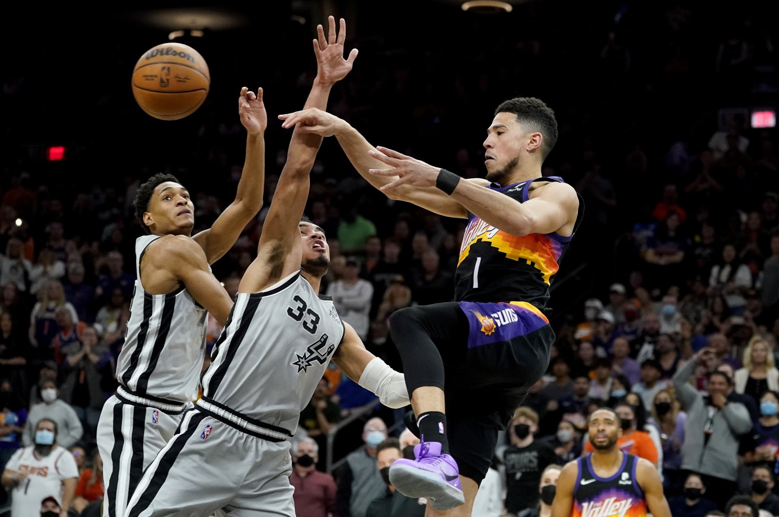 Phoenix Suns guard Devin Booker (R) passes as San Antonio Spurs guard Tre Jones (C) defends during an NBA game, Phoenix, Arizona, U.S., Jan. 30, 2022. (AP Photo)