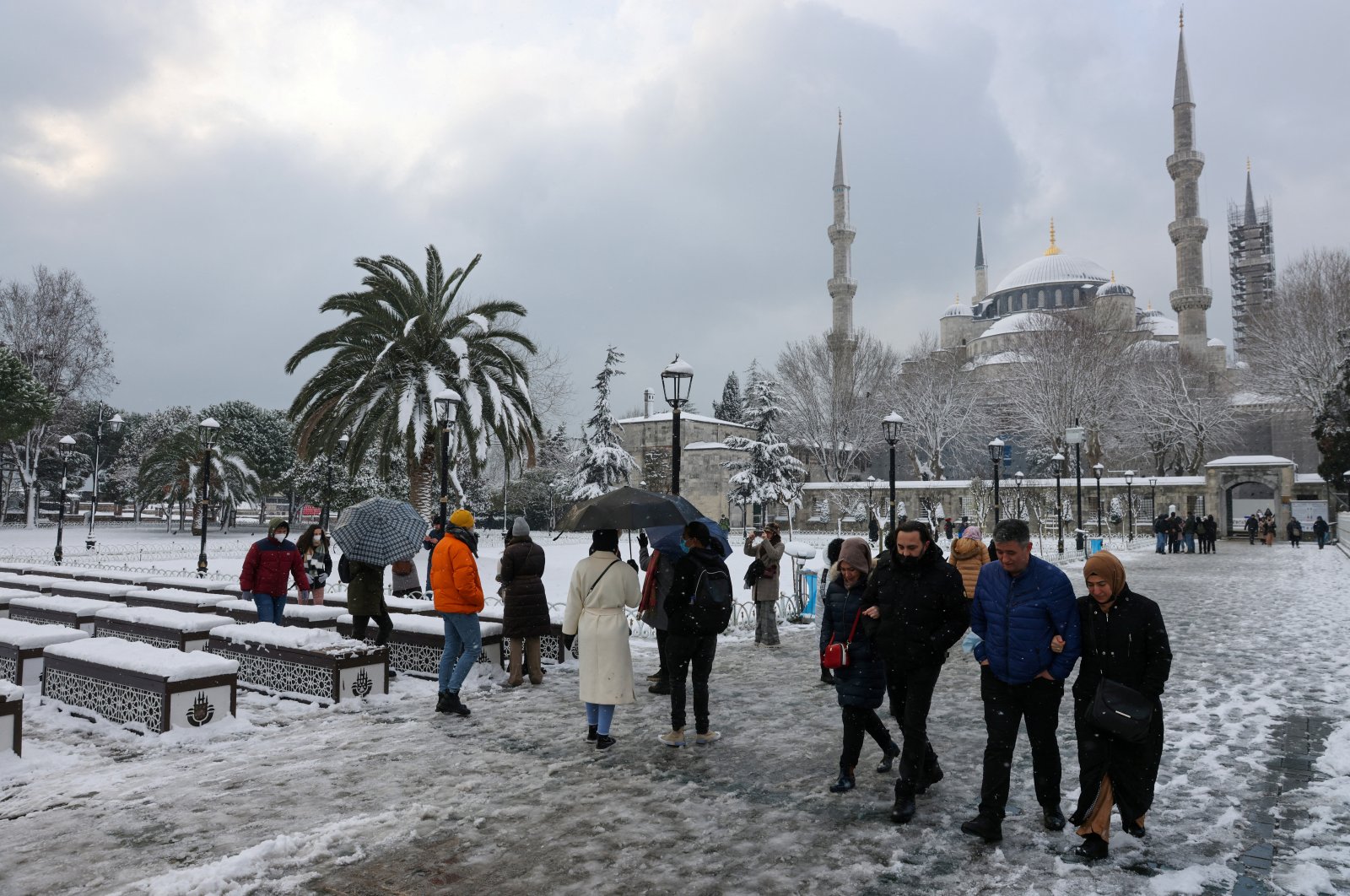 Tourists walk along Sultanahmet Square as the Sultan Ahmet Mosque, popularly known as the Blue Mosque, is seen in the background during a snowy day in Istanbul, Turkey, Jan. 24, 2022. (Reuters Photo)