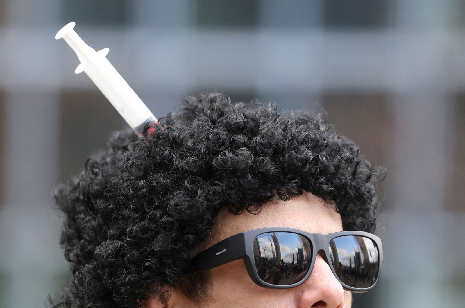 A man wearing a wig with a syringe in it takes part in a demonstration asking for the impeachment of Belgium&#039;s government after restrictions imposed to contain the spread of COVID-19, Brussels, Belgium, Jan. 30, 2022. (Reuters Photo)