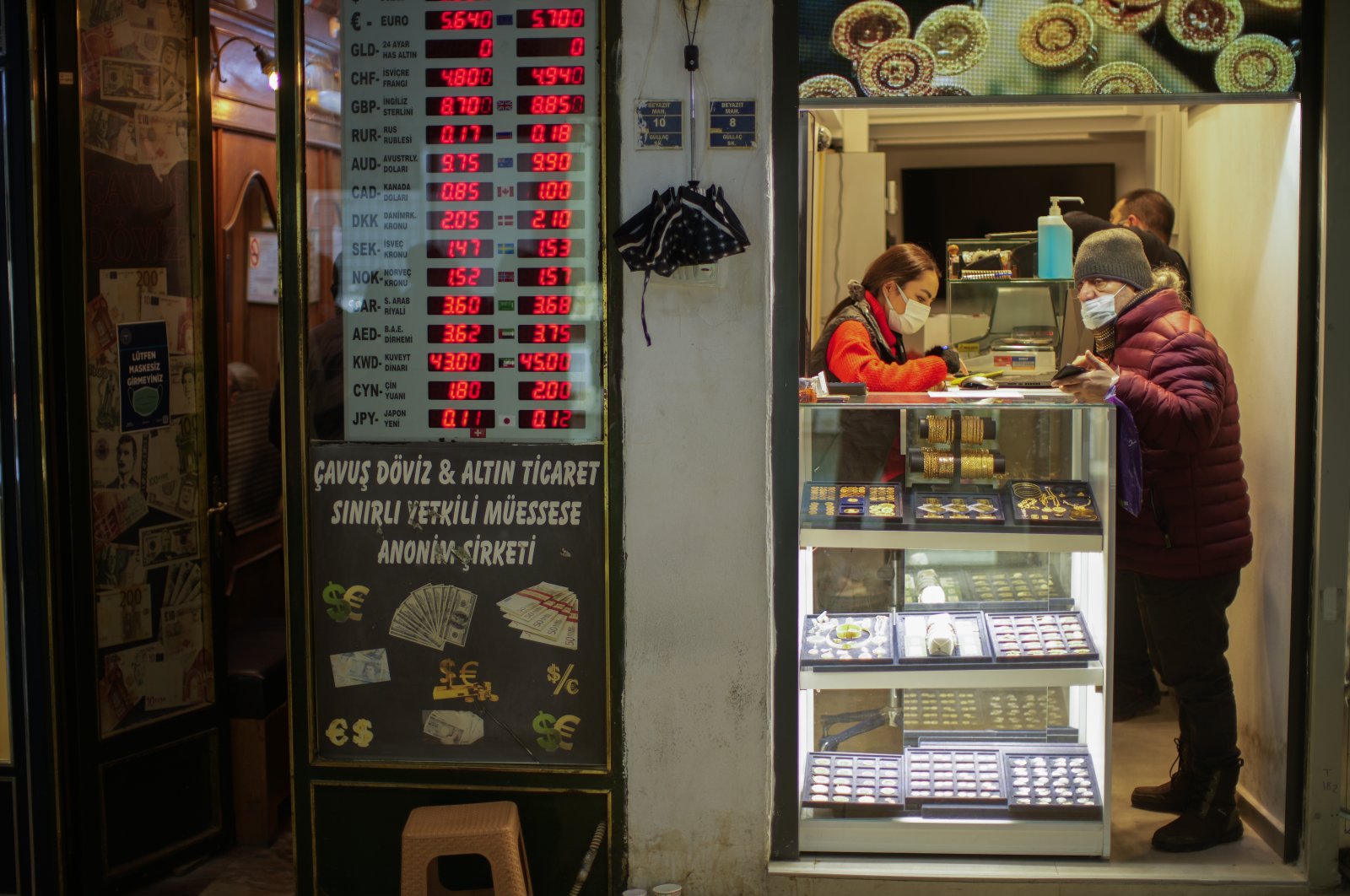 A seller attends a client in a gold shop next to a currency exchange post at the Grand Bazaar in Istanbul, Turkey, Jan. 12, 2022. (AP Photo/Francisco Seco)