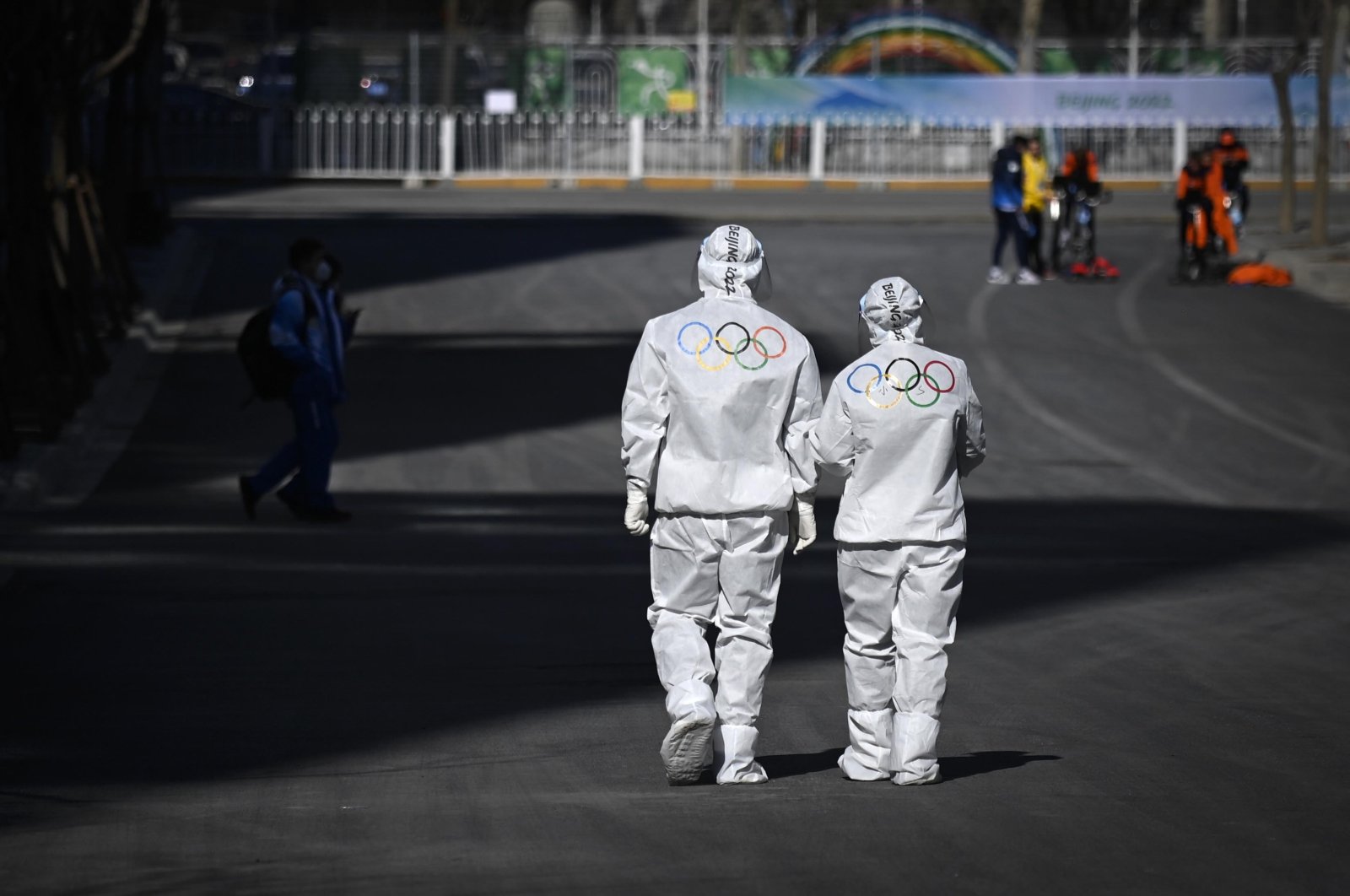 Olympic workers in protective suits walk on a road at the Olympic Village, Beijing, China, Feb. 1, 2022. (AP Photo)