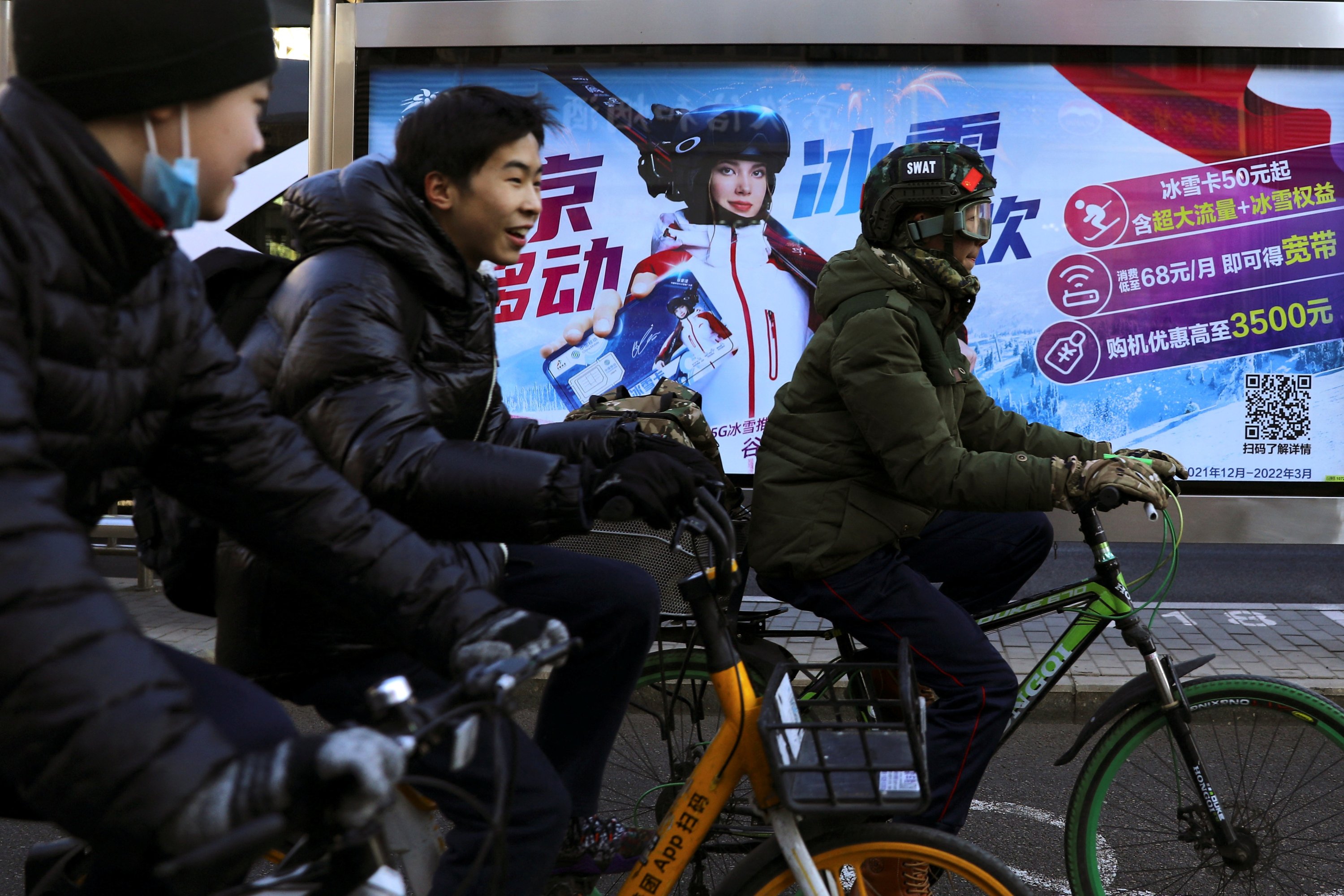 People ride bicycles past an advertisement with an image of Chinese freestyle skier Eileen Gu, Beijing, China, Jan. 11, 2022. (Reuters Photo)