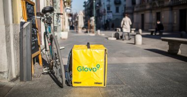 A Glovo delivery backpack is kept next to a delivery bike on the street of Turin, Italy, Feb. 5, 2019. (Shutterstock Photo)