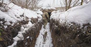 A Ukrainian soldier is followed by a puppy as he walks through a trench at a frontline position in the Luhansk region, eastern Ukraine, Feb. 1, 2022. (AP Photo)