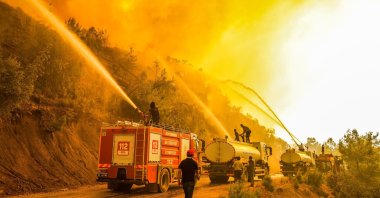 Firefighters spray water on a burning forest, in Manavgat district, in Antalya, southern Turkey, Aug. 11, 2021. (DHA PHOTO)