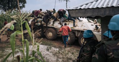 Red Cross volunteers climb onto an armored vehicle of the United Nations mission in DR Congo, MONUSCO, to protect themselves from bullets during an attack by Codeco militia fighters as they attempted to bury the bodies of people killed in Dhedja, 60 kilometers from Bunia, the provincial capital of Ituri in northeastern Democratic Republic of Congo, Dec. 19, 2021. (AFP Photo)