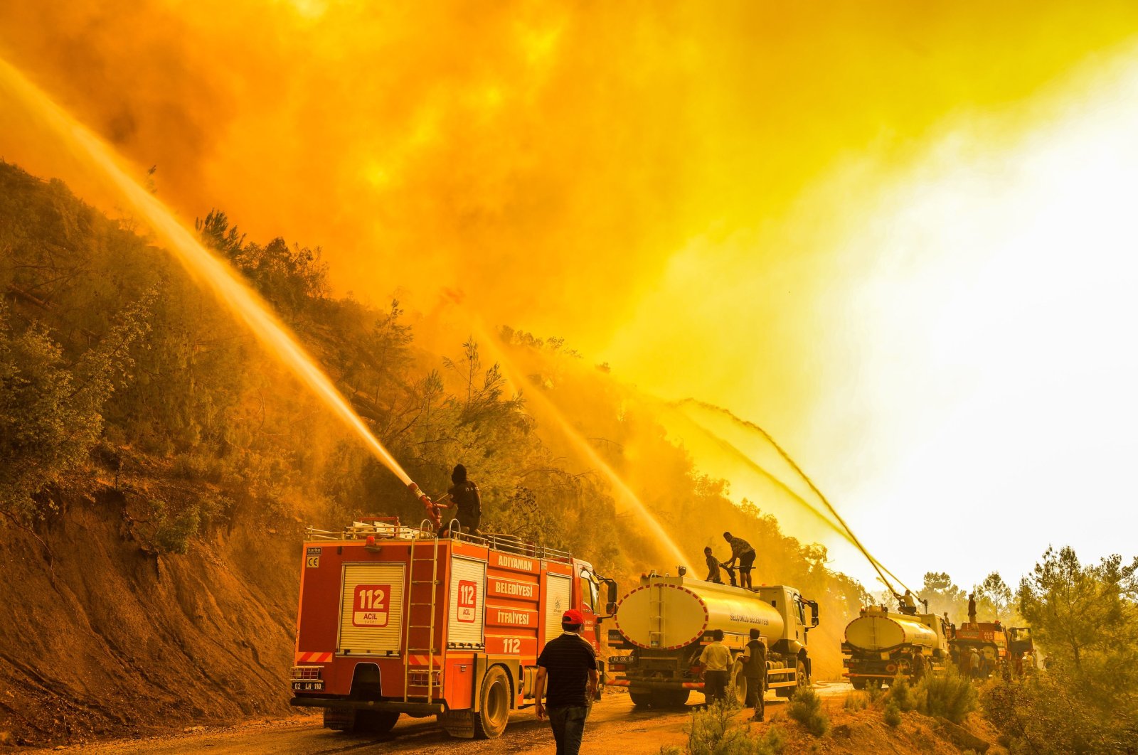 Firefighters spray water on a burning forest, in Manavgat district, in Antalya, southern Turkey, Aug. 11, 2021. (DHA PHOTO)