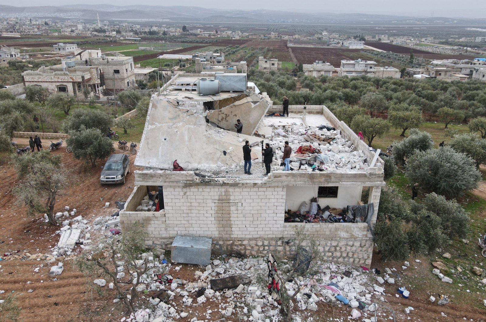 An aerial picture taken by a drone shows people inspecting a damaged building after an alleged counterterrorism operation by U.S. special forces in the early morning in the northern countryside of Idlib, Syria, Feb. 3, 2022. (EPA Photo)