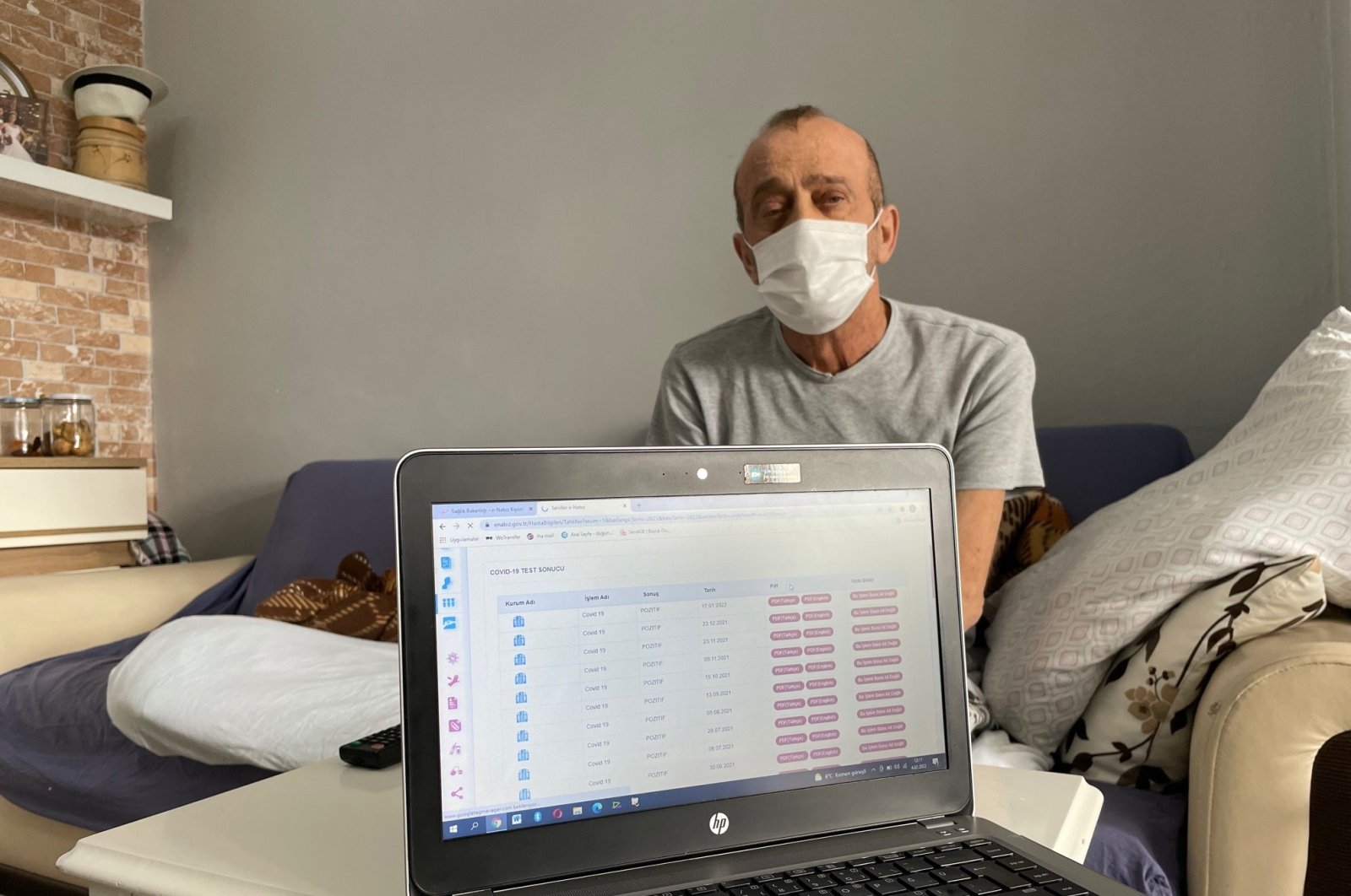 Muzaffer Kayasan sits behind a computer screen showing his positive test results, in his home, in Istanbul, Turkey, Feb. 4, 2022. (IHA PHOTO)