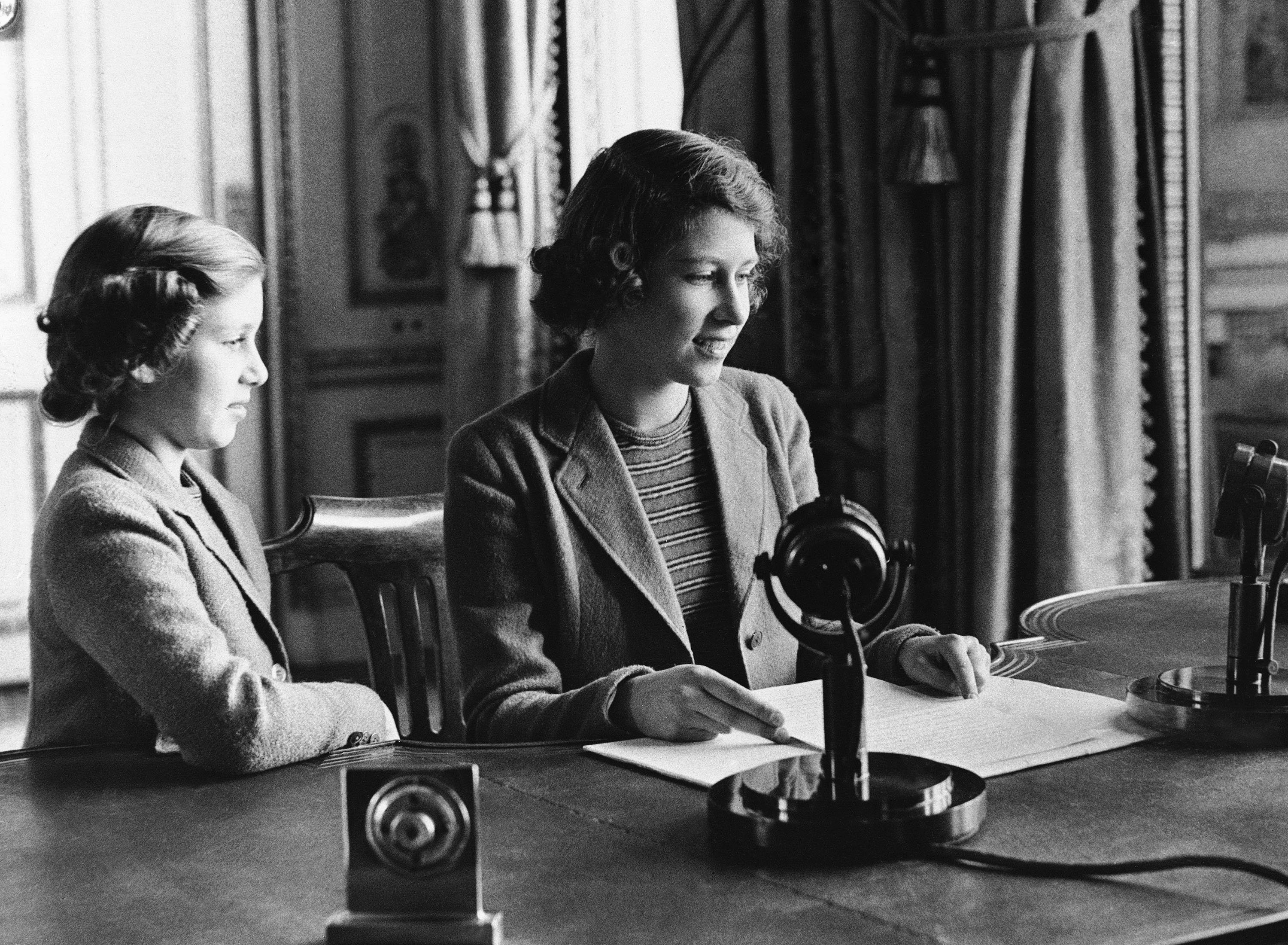 Princess Elizabeth (R), 14-year-old heiress apparent to the British throne, broadcasts a three-minute speech to British girls and boys evacuated overseas with her sister Margaret standing beside her, in London, U.K., Oct. 22, 1940. (AP Photo)