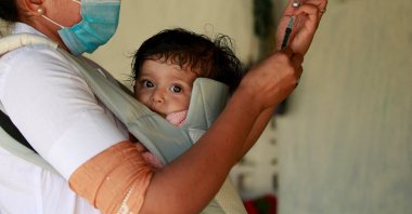A health care worker, carrying her daughter, prepares to give a dose of vaccine against COVID-19 to a villager in Lodhida village in Rajkot district in the western state of Gujarat, India, Feb. 1, 2022. (Reuters Photo)