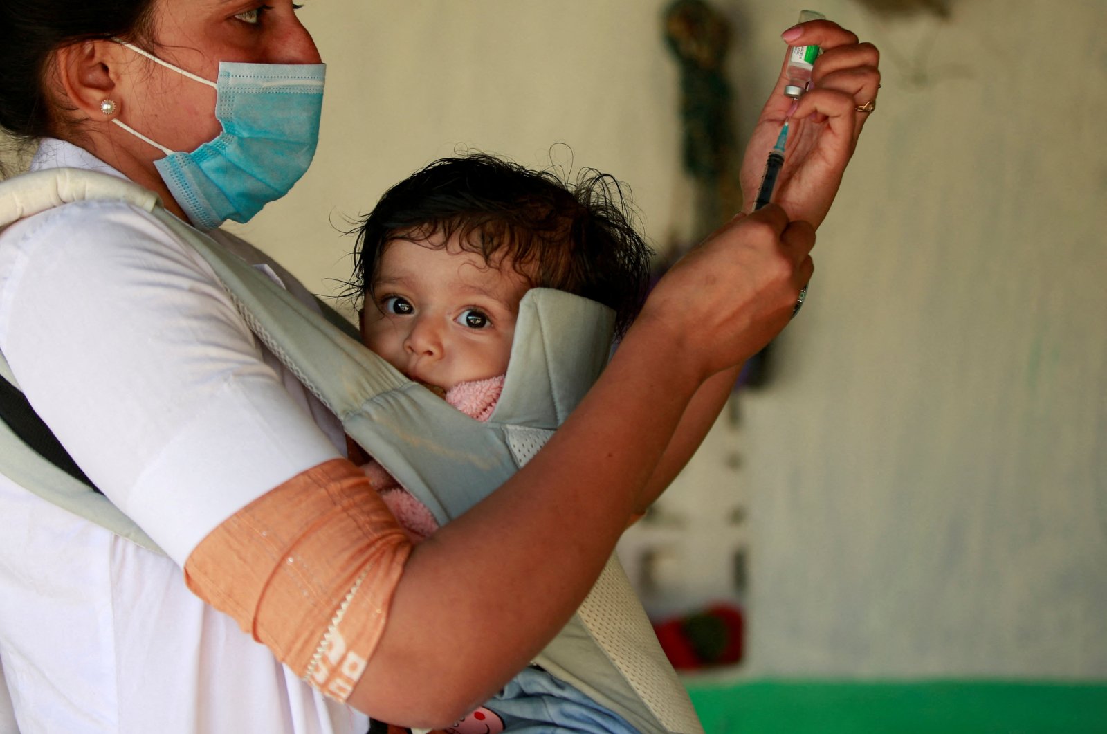 A health care worker, carrying her daughter, prepares to give a dose of vaccine against COVID-19 to a villager in Lodhida village in Rajkot district in the western state of Gujarat, India, Feb. 1, 2022. (Reuters Photo)