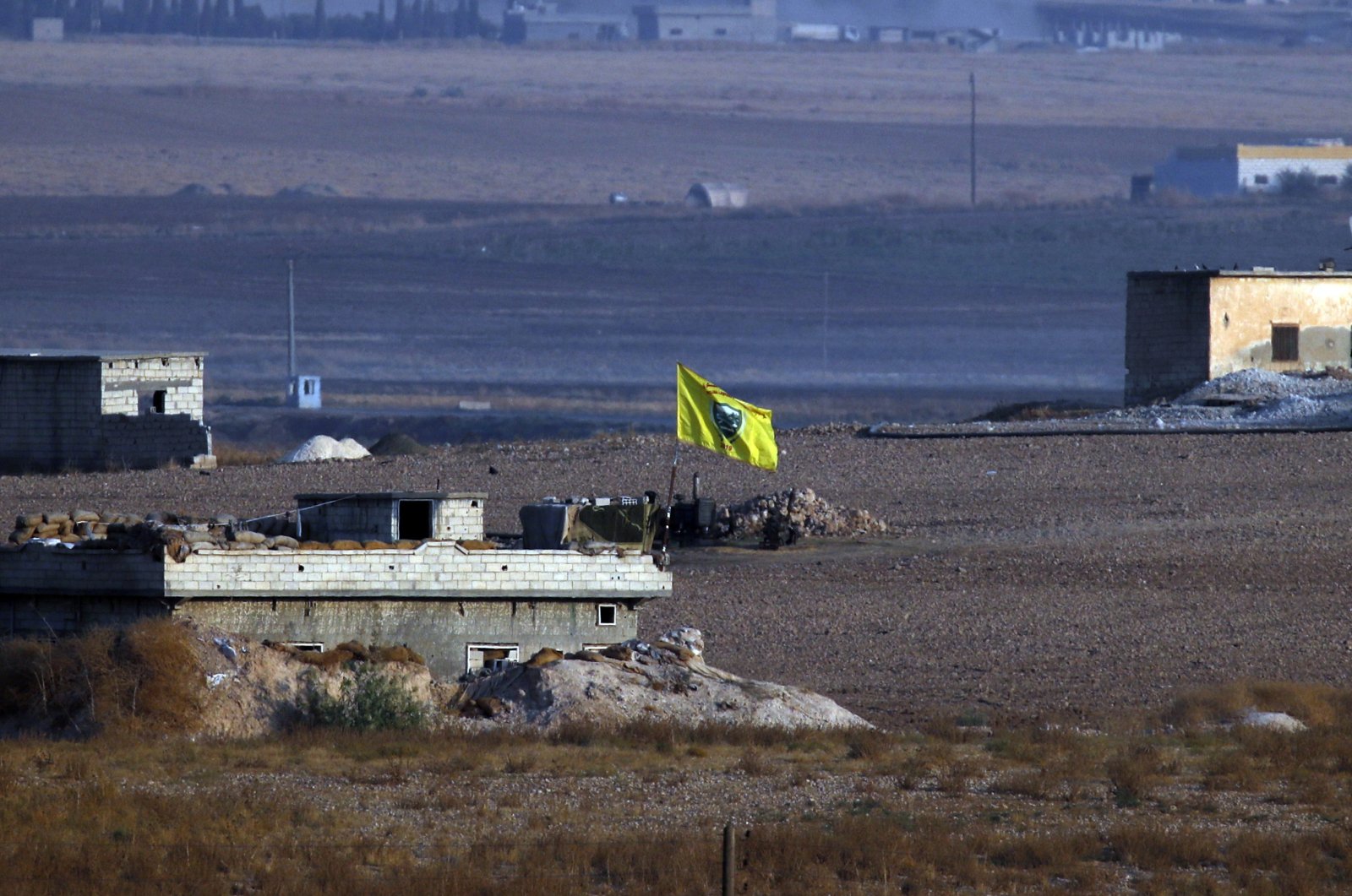 In this photo taken from the Turkish side of the border between Turkey and Syria, in Akçakale, Şanlıurfa province, southeastern Turkey, and shortly after the Turkish operation inside Syria started, YPG/PKK flag flies on a building, Wednesday, Oct. 9, 2019. (AP File Photo)