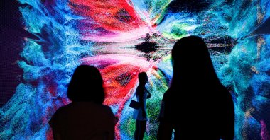 Visitors are pictured in front of an immersive art installation titled "Machine Hallucinations – Space: Metaverse" by Turkish media artist Refik Anadol, which will be converted into NFT and auctioned online at Sotheby's, at the Digital Art Fair, in Hong Kong, Sept. 30, 2021. (Reuters Photo)