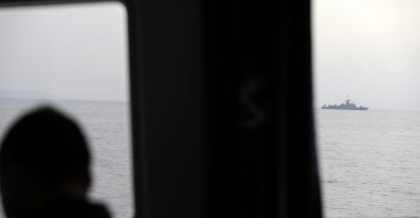 A Greek officer watches a NATO warship on the Aegean Sea near the Greek island of Lesbos (Midilli), just a few kilometers off Turkey's Ayvalık, March 17, 2017. (AP File Photo)
