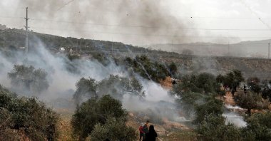 Palestinian protesters retreat as tear gas canisters fall amid clashes with Israeli security forces following a demonstration against settlements in the village of Beita in the occupied West Bank, Palestine, Feb. 4, 2022. (AFP Photo)