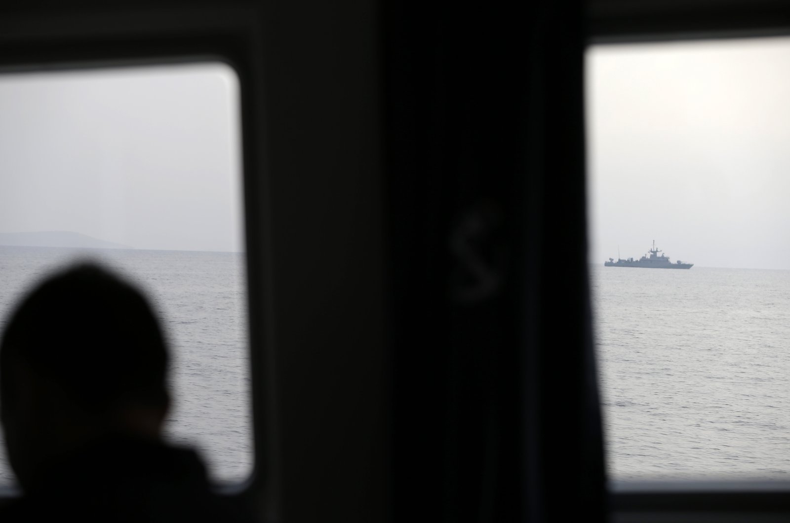 A Greek officer watches a NATO warship on the Aegean Sea near the Greek island of Lesbos (Midilli), just a few kilometers off Turkey&#039;s Ayvalık, March 17, 2017. (AP File Photo)