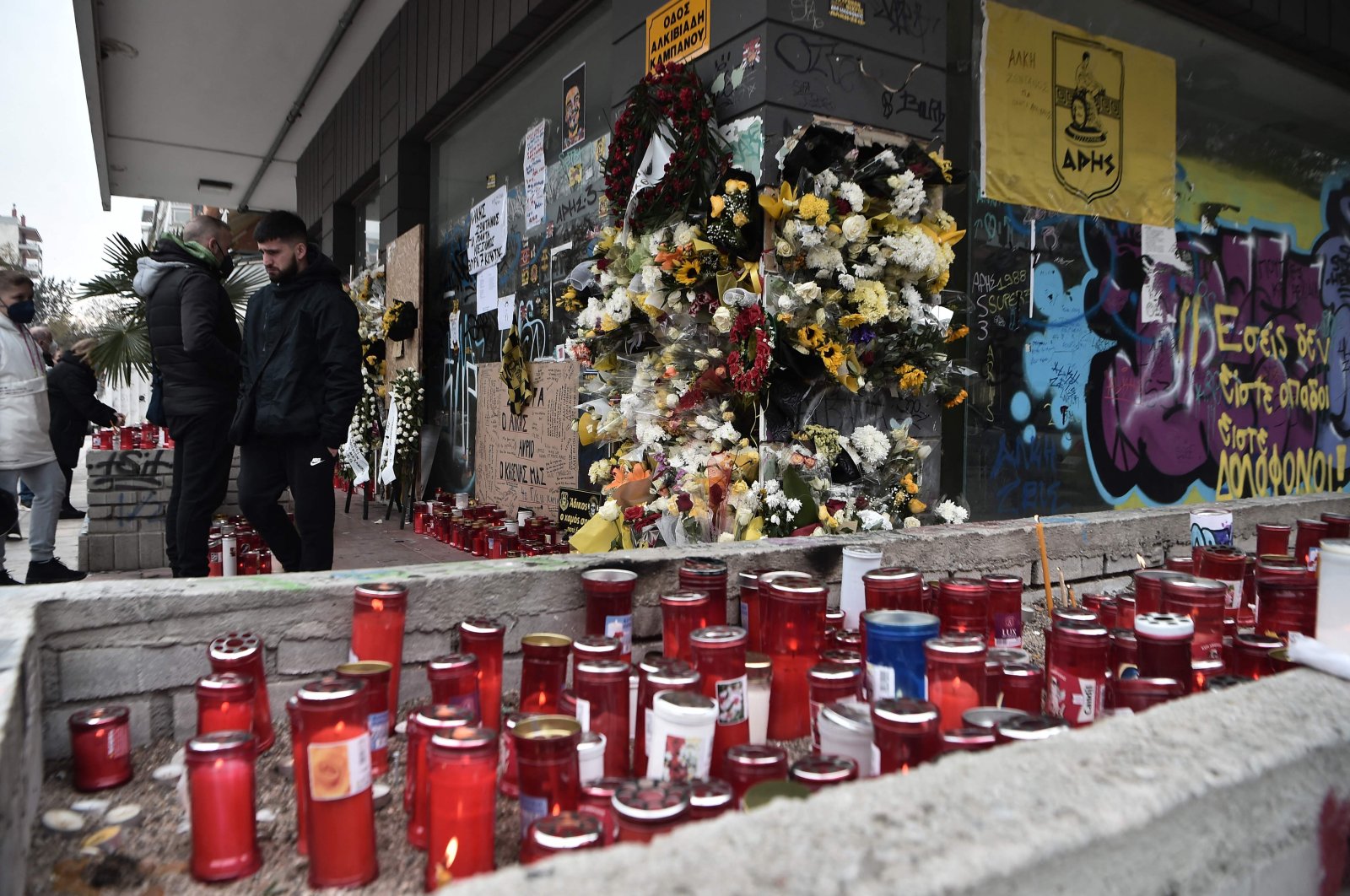 People stand at the spot where a teenager was stabbed to death outside the Aris FC stadium, Thessaloniki, Greece, Feb. 7, 2022. (AFP Photo)