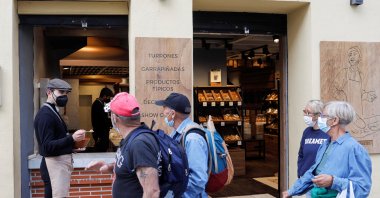 A worker offers candied sunflower seeds to tourists outside a food shop in Ronda, Spain, Feb. 3, 2022. (Reuters Photo)