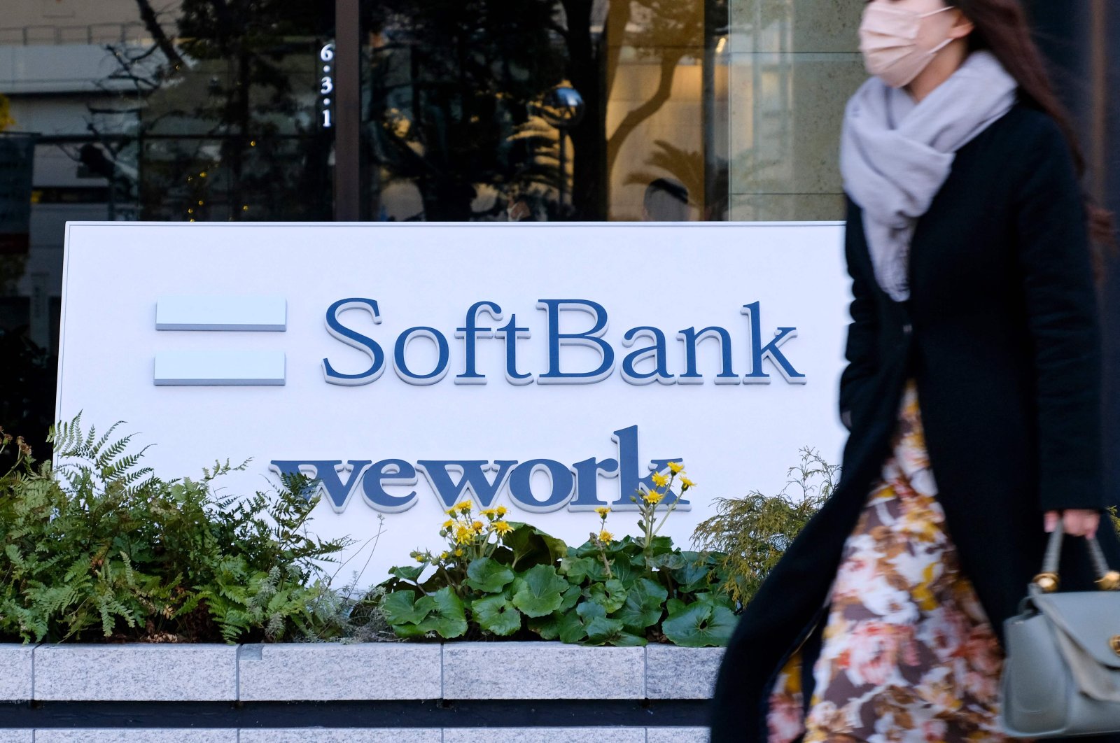 A pedestrian walks past signage outside the building where the SoftBank Group headquarters is located in Tokyo, Japan, Feb. 8, 2022. (AFP Photo)