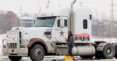 A man shovels around a truck as vehicles block the Sir John A. McDonald Parkway west of Parliament Hill as truckers and their supporters continue to protest against the COVID-19 vaccine mandates in Ottawa, Ontario, Canada, Feb. 8, 2022. (Reuters Photo)