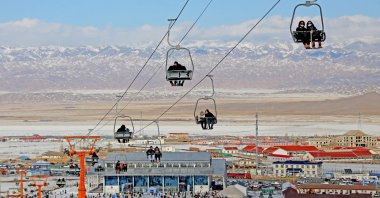 Skiers and snowboarders riding chairlifts at a ski field in Hami, Xinjiang, China, Feb. 3, 2022. (AFP Photo) 