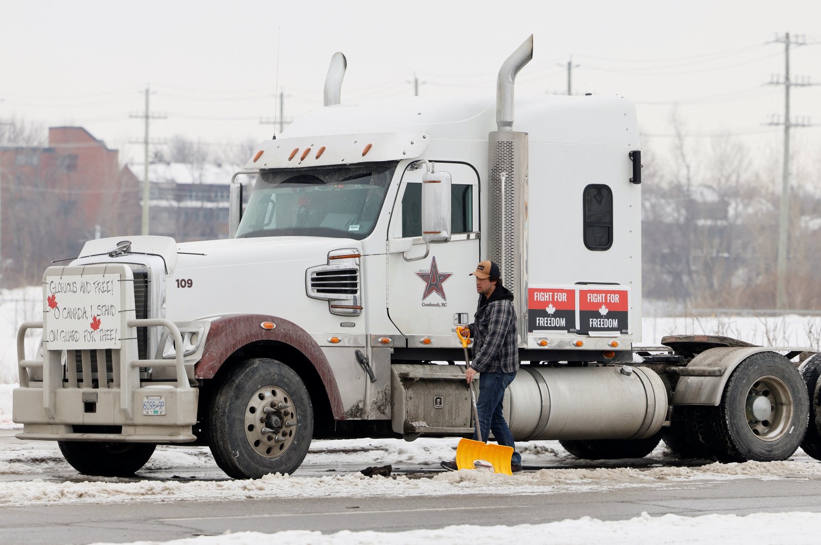 A man shovels around a truck as vehicles block the Sir John A. McDonald Parkway west of Parliament Hill as truckers and their supporters continue to protest against the COVID-19 vaccine mandates in Ottawa, Ontario, Canada, Feb. 8, 2022. (Reuters Photo)