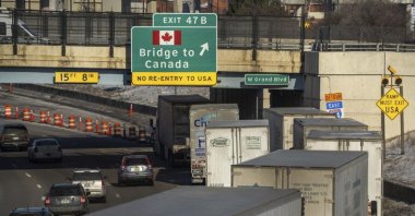 A small line of semi-trailer trucks lineup along northbound I-75 in Detroit as the Ambassador Bridge entrance is blocked off for travel to Canada, Feb. 8, 2022. (Detroit Free Press via AP)