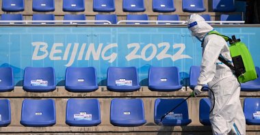 A staff member wearing personal protective equipment (PPE) disinfects the stands after an event during the Beijing 2022 Winter Olympic Games in Beijing, China, Feb. 9, 2022. (AFP Photo)