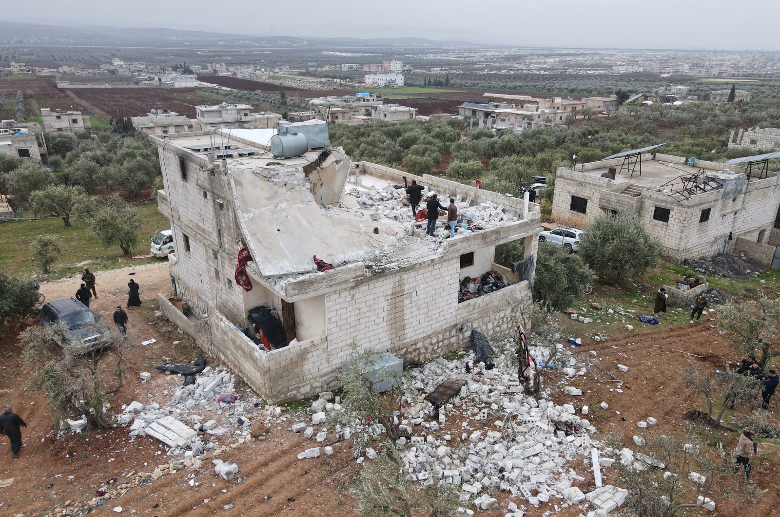 An aerial picture taken by a drone shows people inspecting a damaged building after an alleged counterterrorism operation by U.S. special forces in the early morning in Atmeh village in the northern countryside of Idlib, Syria, Feb. 3, 2022. (EPA Photo)