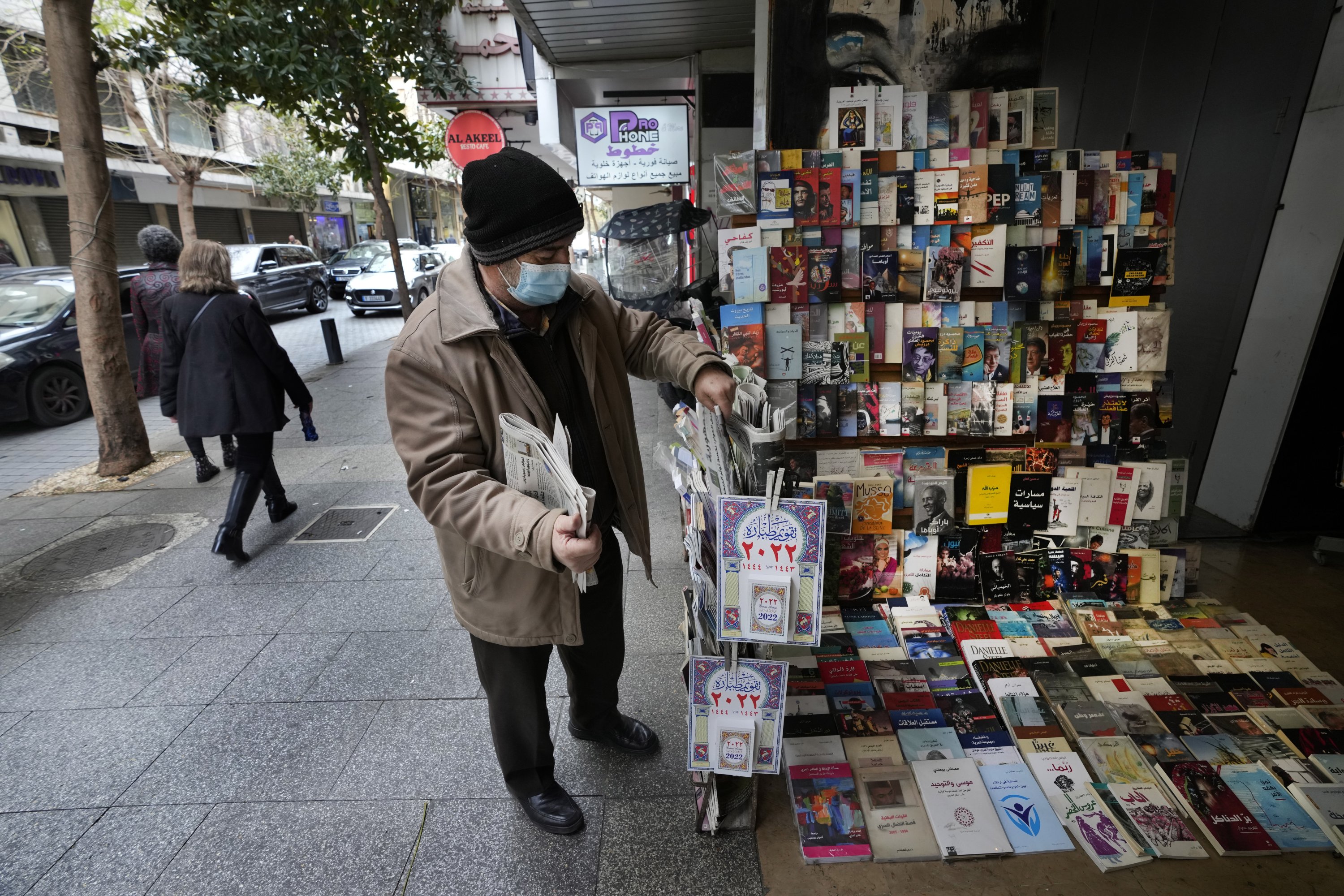 Naim Saleh, a newspapers, magazines and books street vendor, displays newspapers at Hamra street, in Beirut, Lebanon, Jan. 14, 2022. (AP Photo)